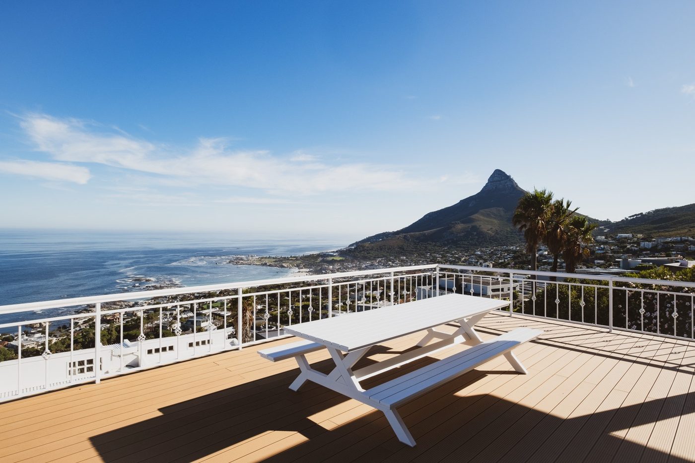 A wooden deck at the villa with a bench, looking across Camps Bay to Lion's Head.